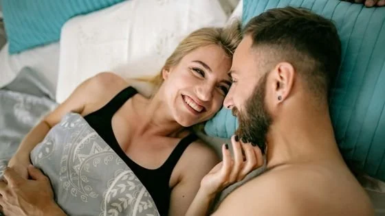 couple in bed and smiling indicating mutual power and respect.