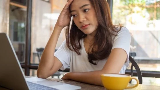 woman looking overwhelmed in front of computer indicating functioning not same as wellness.