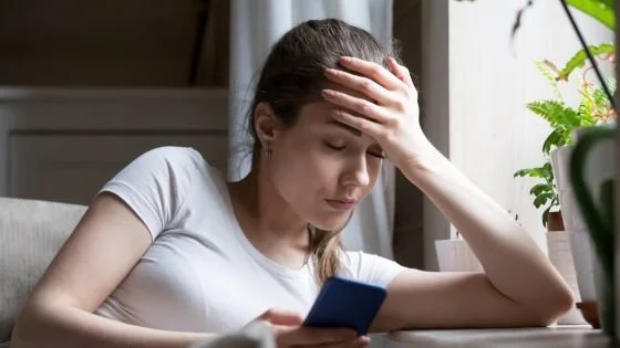 woman alone looking sad at her phone indicating the abrupt nature of some relationships ending over text and how we can honor the relationship ending in couples therapy.