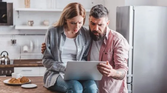 couple looking concerns at computer indicating trying to involve AI in an active role in couple's therapy and the pitfalls of that.