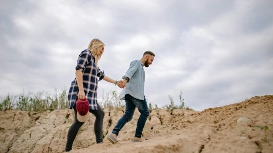 couple hiking up mountain holding hands indicating doing the collaborative work of repatterning their relationship.