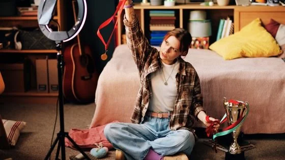 woman showing off trophies to the camera alone in her room indicating the cost of wanting to win over being connected. Shifting this approach can be learned in couples counseling.