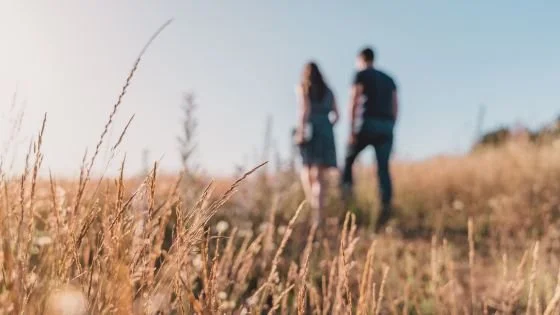 couple walking through a field, them fuzzy in background. Indicating zooming out to reconcile a relationship.