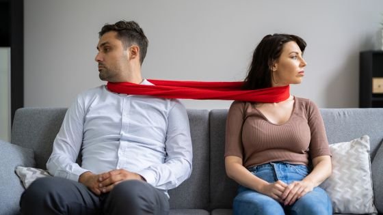 couple stuck together with a scarf indicating being stuck in a cycle.