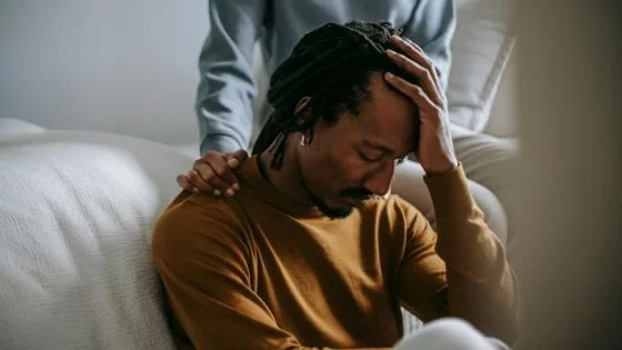 distraught black man being comforted by partner, indicating the importance of checking on your partner and not assuming happiness or improvement.
