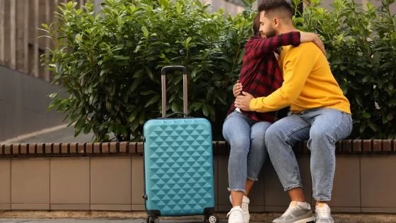couple hugging. One with a suitcase. Indicating one person leaving to take space to figure out their relationship.