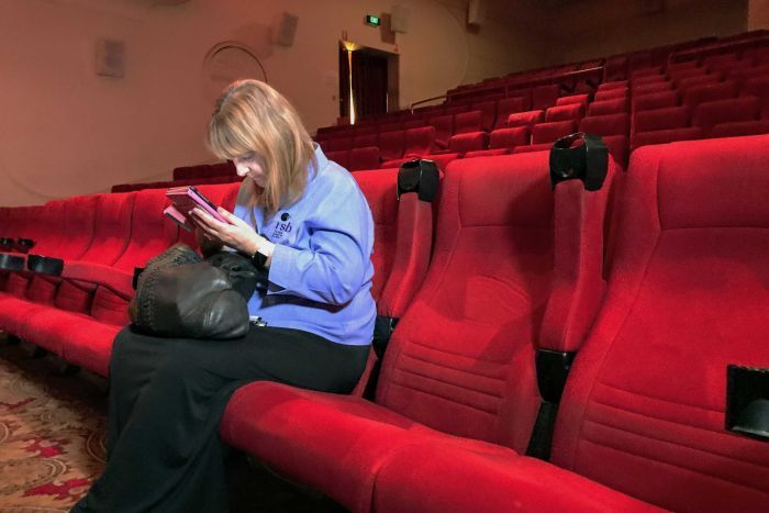 Cinemagoers are usually urged to switch off mobile phones when the lights dim for a movie, but a new app for the vision-impaired will transform their device and film-going experience. Adelaide woman Sarah Savage said her impairment meant she had never before been to the cinema, and she missed out as well when she and her husband watched TV or movies at home. "I miss most of the detail, especially if there's lots of darkness," she said. The MovieReading app detects the point the film is at, via the phone's microphone, and streams a detailed descriptive audio track, which tells the user what is appearing on the big screen.