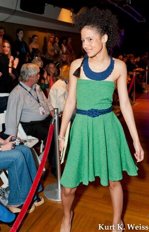Model walks the runway at Knoxville Fashion Wek 2016 in bright green strapless tea length dress wth bright blue belt and necklace