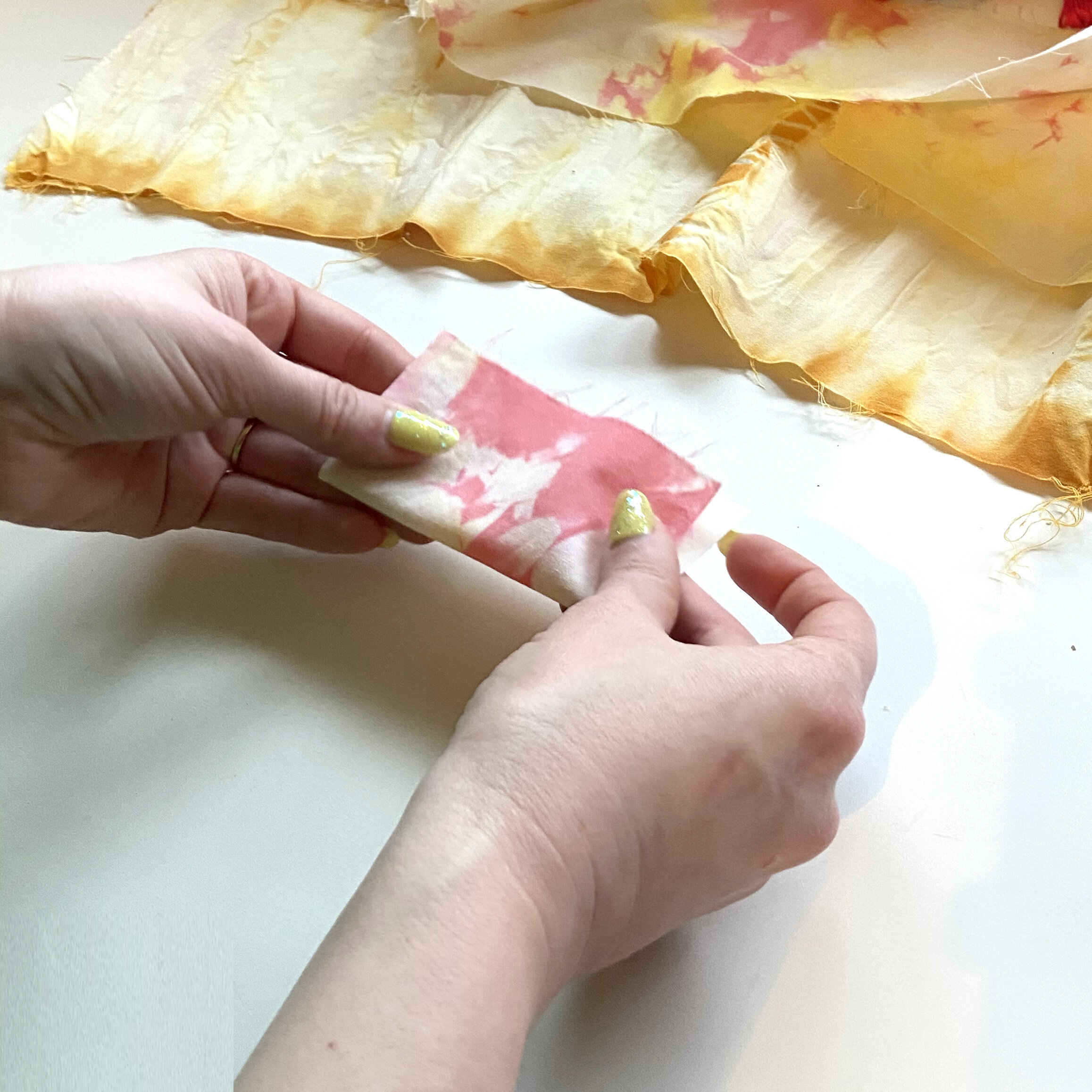 Alaina folds a small scrap of pink tie dye fabric in half