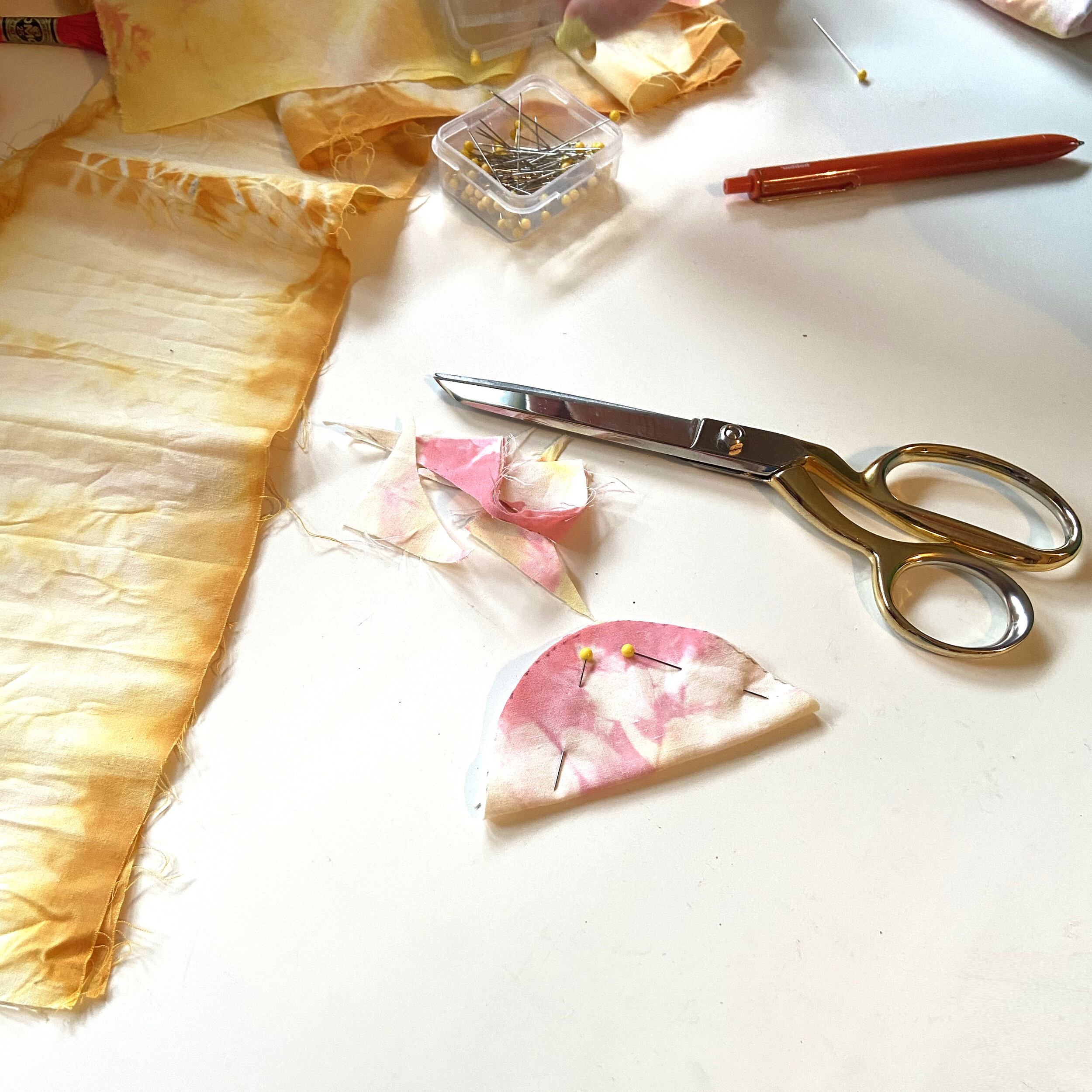 supplies for DIY cat toy, scissors, fabric, and pins laid out on table