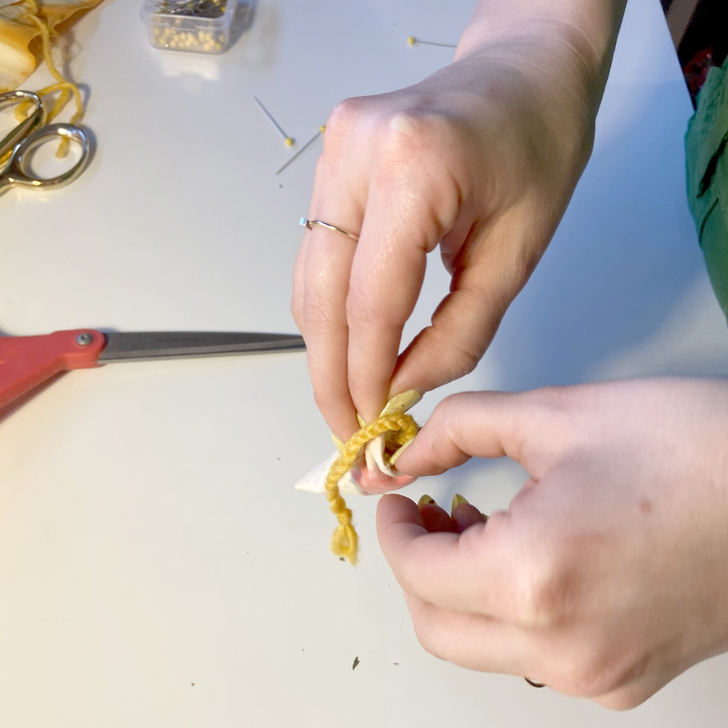 Alaina tucks braided yarn into cat toy