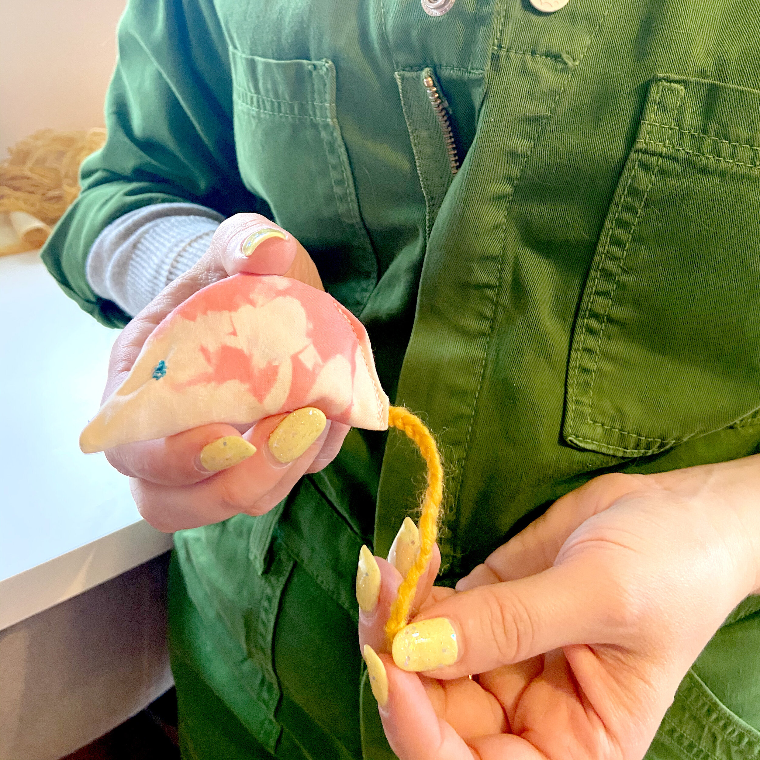 Alaina holds handmade mouse cat toy made with pink tie dye fabric.