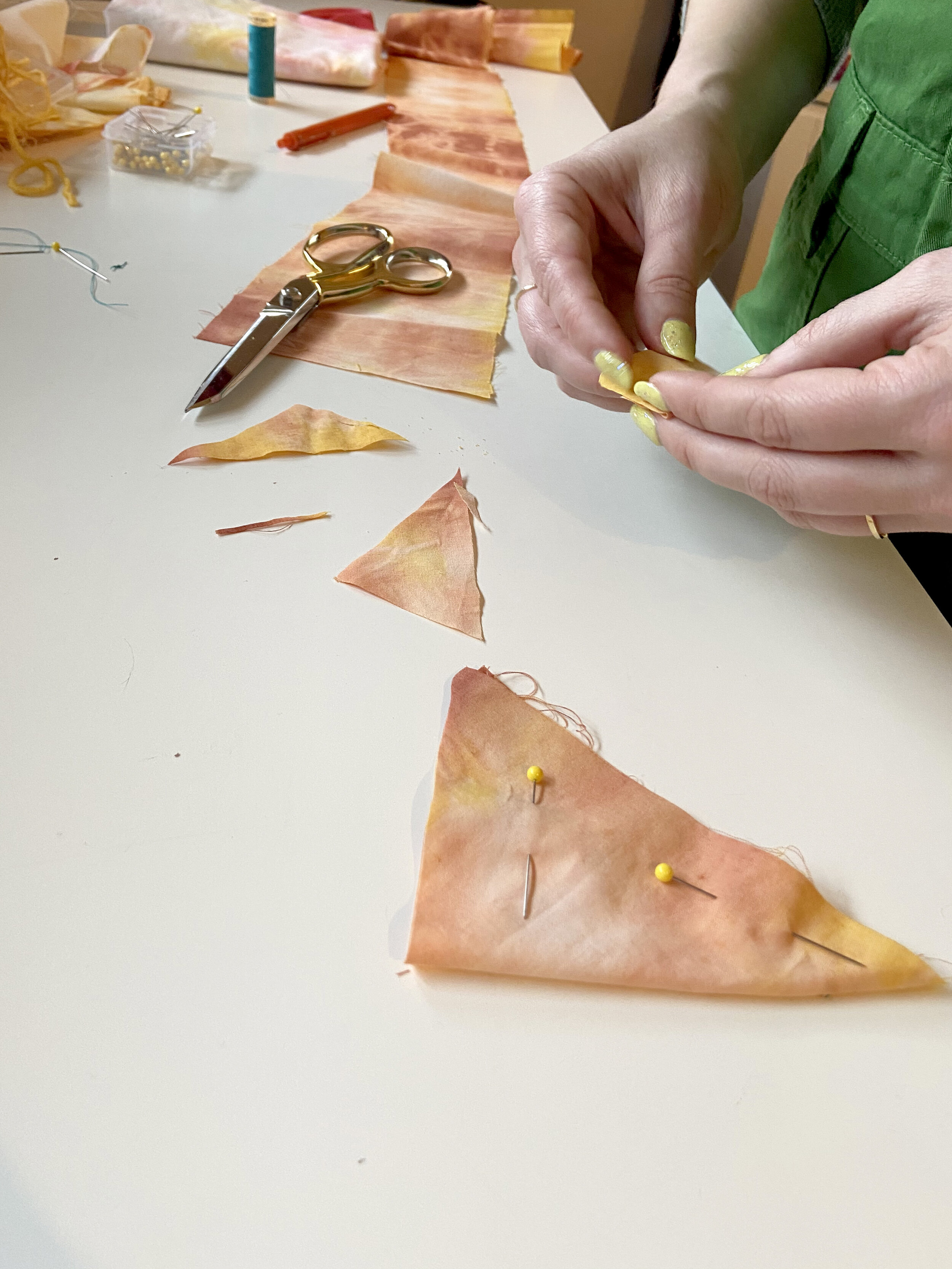 Alaina folds and pins scrap tie dye fabric in a triangle shape to make a bunny carrot toy