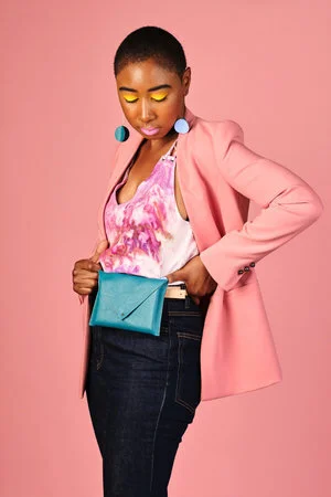 A young woman shows off her teal fanny pack style belt bag.