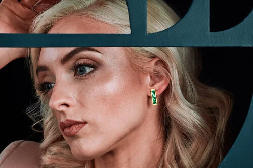 A closeup portrait of a blonde model wearing the long bar geo studs in forest marble. 