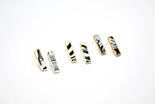 Three sets of the black and white marbled long bar studs against a white backgound. 