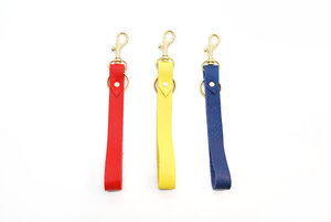 Three hand riveted leather wrist strap key chains in red, yellow, and blue. 