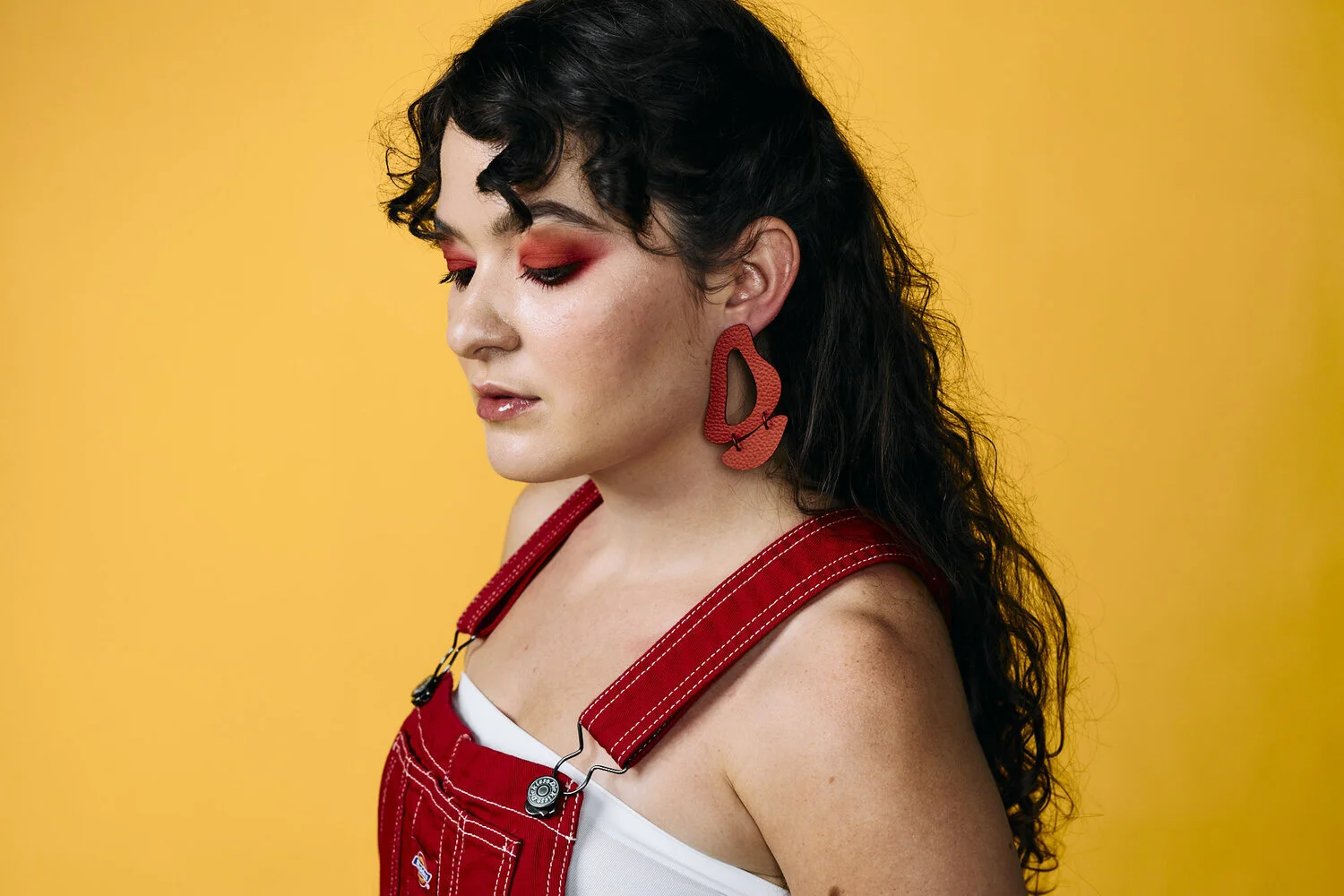 Daniella wears the red Inferno Earrings with red overalls.