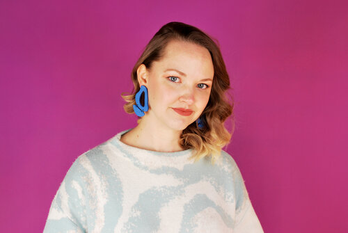 Alaina styles bright Matisse blue leather cutout earrings with a soft blue sweater and big curly hair.