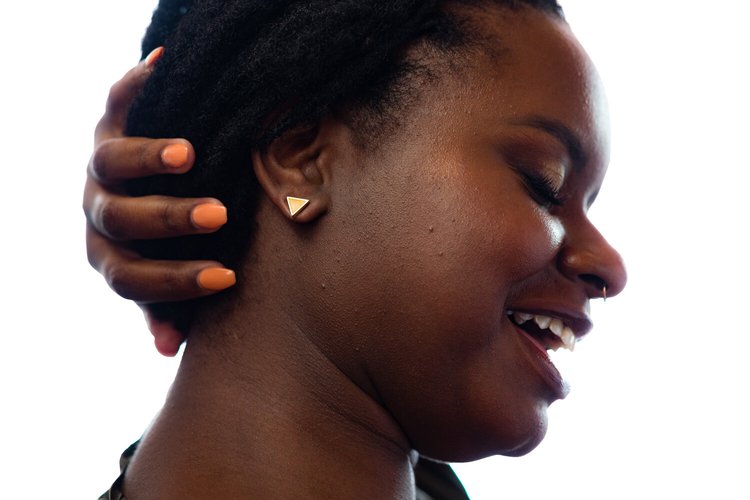 a model laughs and holds her hair back to show off triangle geo studs in citrine yellow