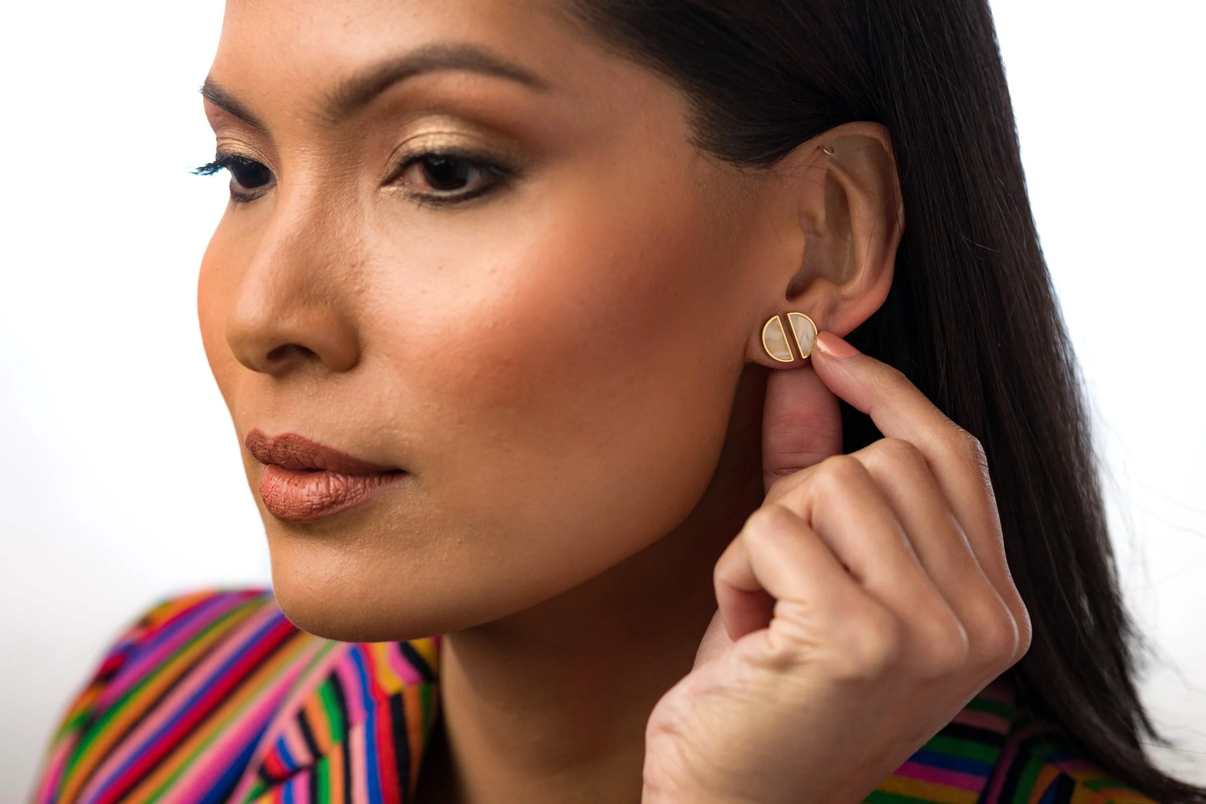 un mannequin avec un maquillage pêche éclatant porte astucieusement une paire de clous de quartz en cristal demi-lune dans une oreille avec deux piercings