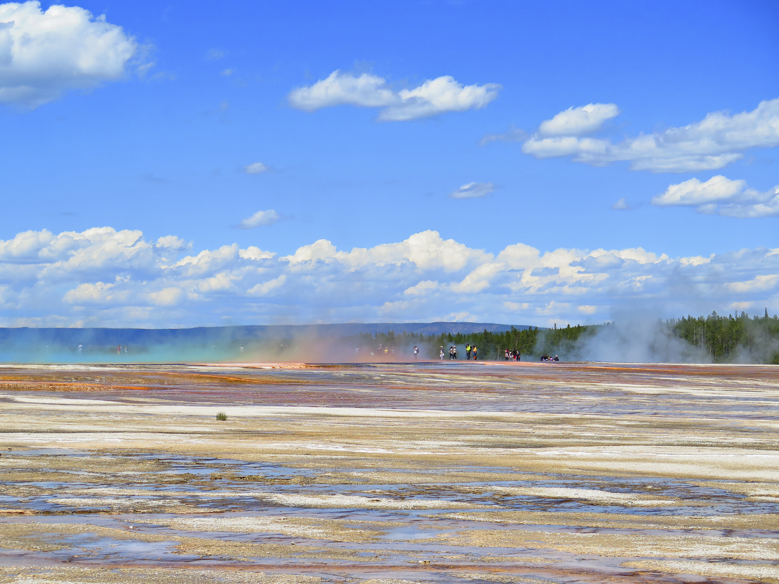 People walking through the steam coming out of the Grand Prismatic Spring.