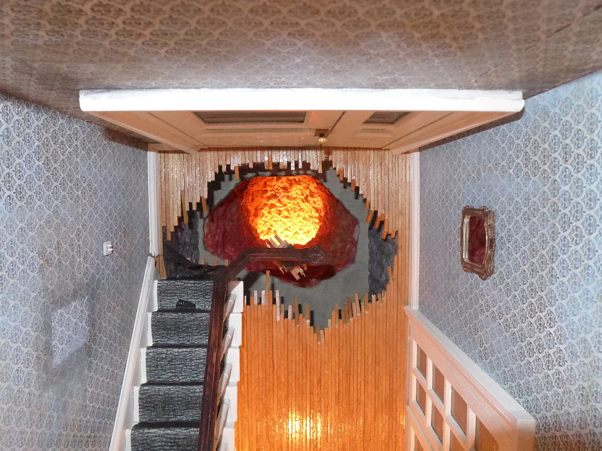 'Tom Ridge' Illuminated Sinkhole Detail Wood framing, Metal mesh, Mahoghany Handrail, Moving Blankets, Cart, Fiberglas Insulation, Metal Floor Grates, Cast Iron Window Weights, Audio Approx: 18’L x 3’W x 12’H 2014 This view shows illuminated sinkhole (as viewer sees it within tunnel). The sinkhole plunges through the foyer and an interstitial basement space before descending into a shaft which rises up and out of eye-shot and is lined in a flesh-like substance (actually fiberglas insulation).