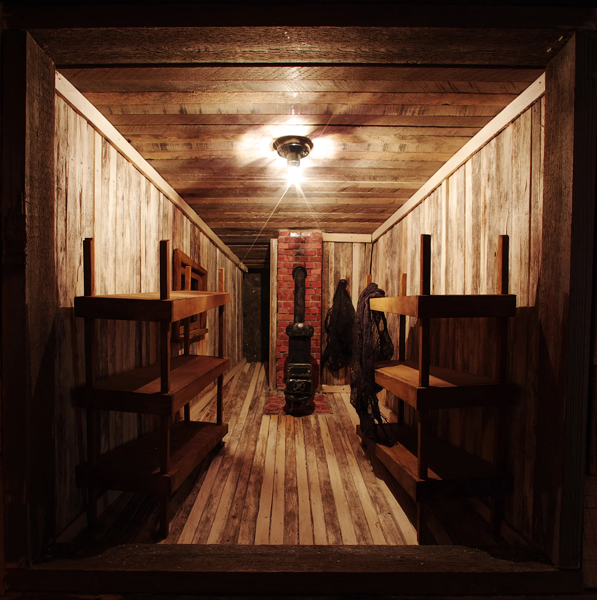 ‘Beneath / Suspicion' Detail at Camp 104 Vignette Wood framing, oak pallet wood, drapery, nightlights, kiln-burned pine tar, incense, muslin. glass view lenses, fiberglas insulation, audio track. Tunnel Portion- 3’W x 2’-8”H x approx. 120’L 2013 Image credits: Gordon Pellegrinetti.