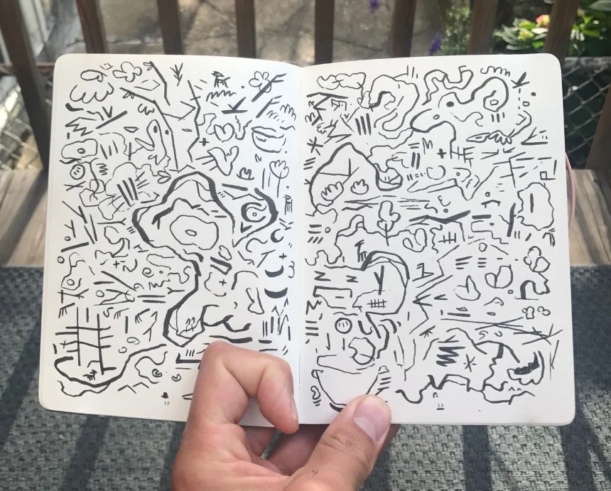 Matthew holding open a page of his sketchbook.