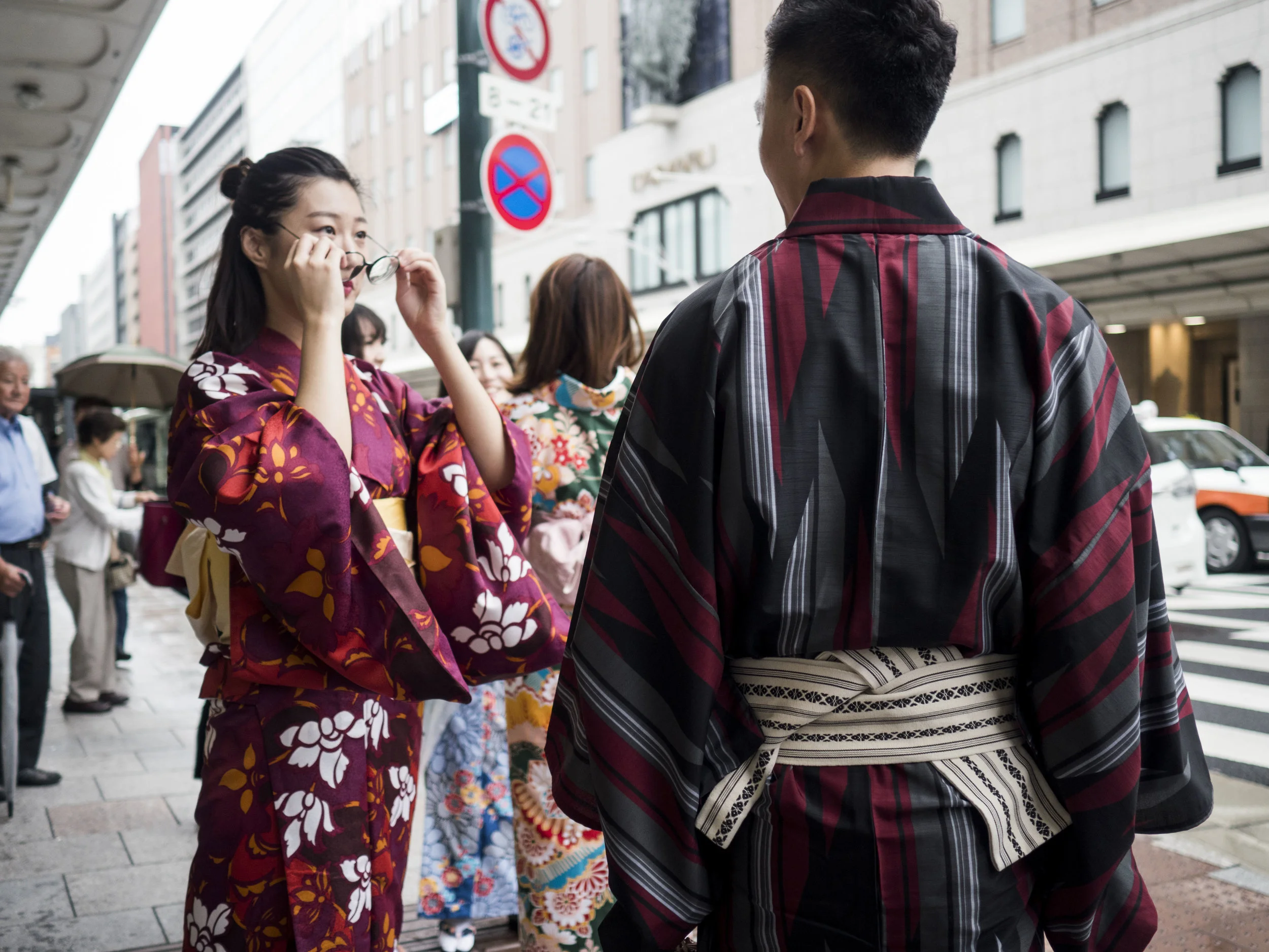Taken late evening (darker than it looks here), so wide open out of need. Focus fell on the man's Kimono, but the story can still unfold because the bokeh is neither too fast/strong in fall off nor too irregular to bear. There is still a snap to the man's back, but the eye drifts to the woman and then further into the image. I feel this makes a more complicated and usable image.