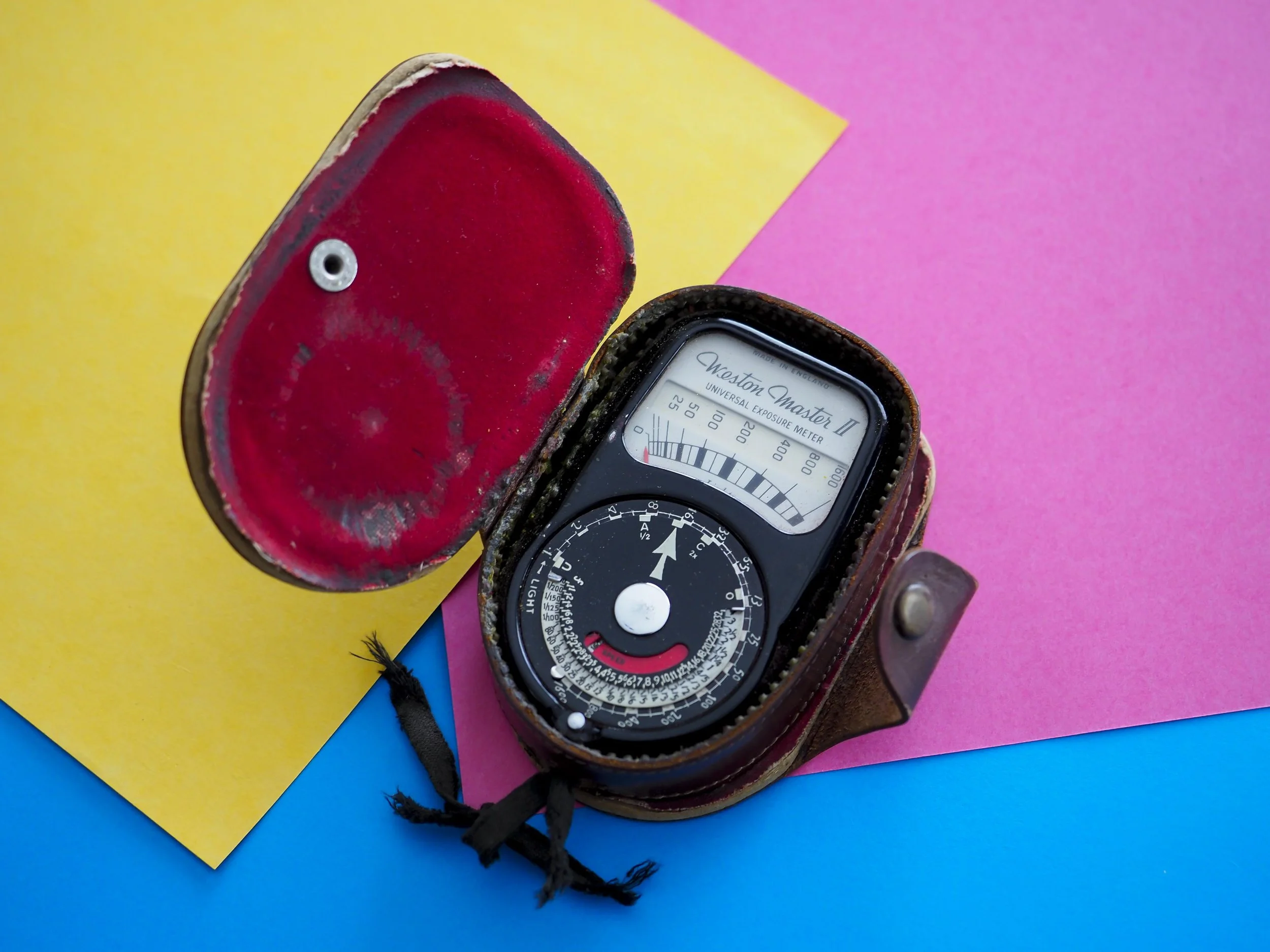 Above is an old, but still working incident light meter and three sheets of paper that would all be roughly “average” tones (as is grass, tarmac, blue denim, low angle blue sky, medium brown hair etc). The light meter would be pointed towards the light source from the subject, giving the photographer an accurate measure of actual light falling on the subject (not reflected off of it). The paper on the other hand can be placed in open light, then a camera, reflected light meter measurement taken off of it, giving you an accurate “average” reading. Either way, the reading would be technically accurate. For the sake of consistency, the colour usually used is “18% grey” or a grey card, but any medium tone colours have an identical effect.