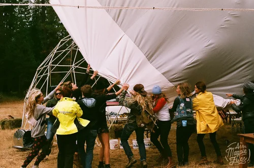 Women working together to save the tarp off of the Escape Collective Dome Saturday Morning.