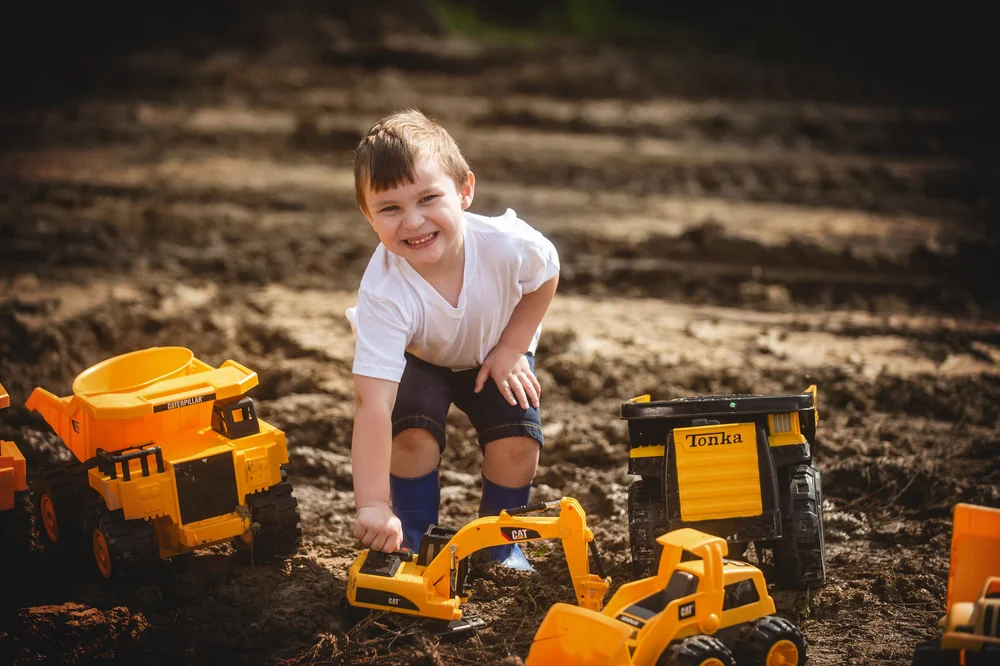 Child laughing while playing with yellow toy trucks