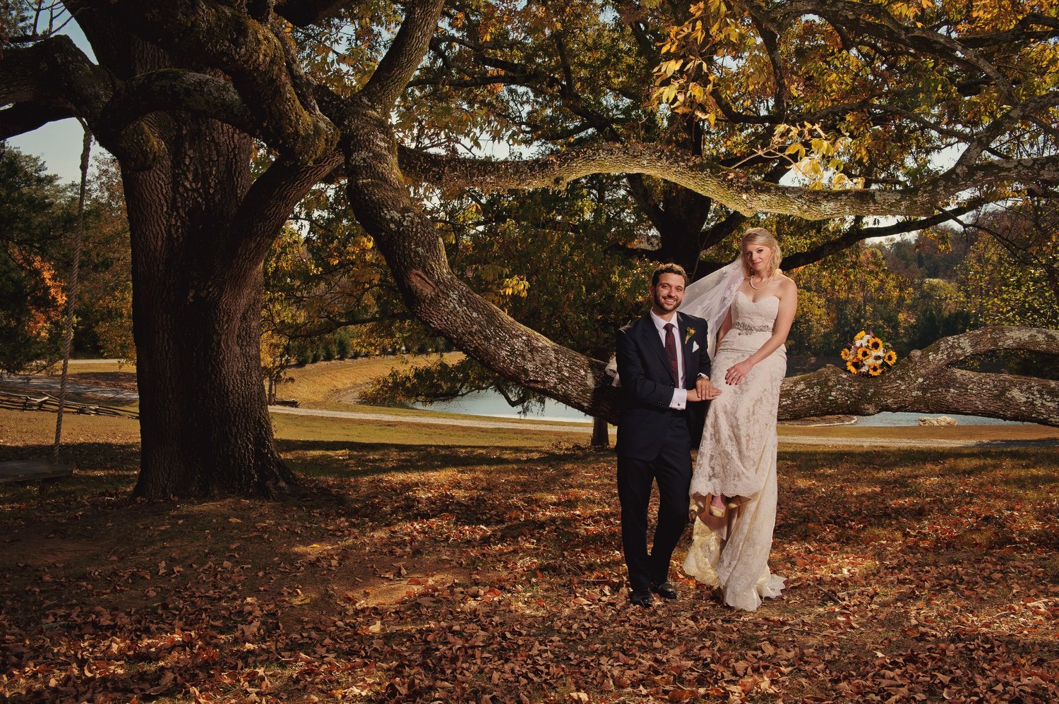 Newlywed couple standing together beneath a sprawling oak tree