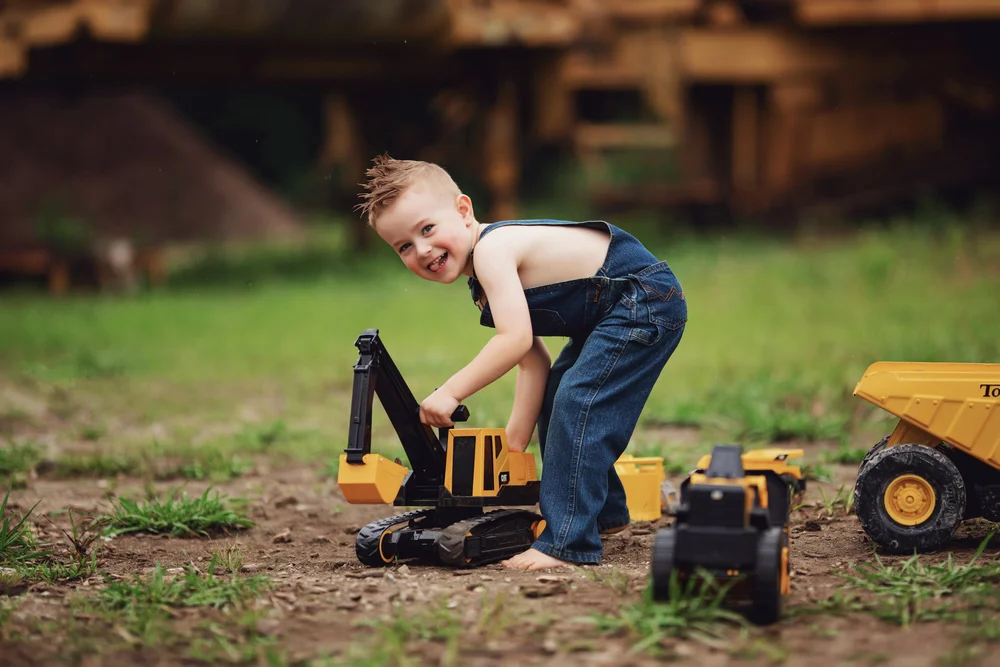 Child climbing onto a toy excavator during muddy play