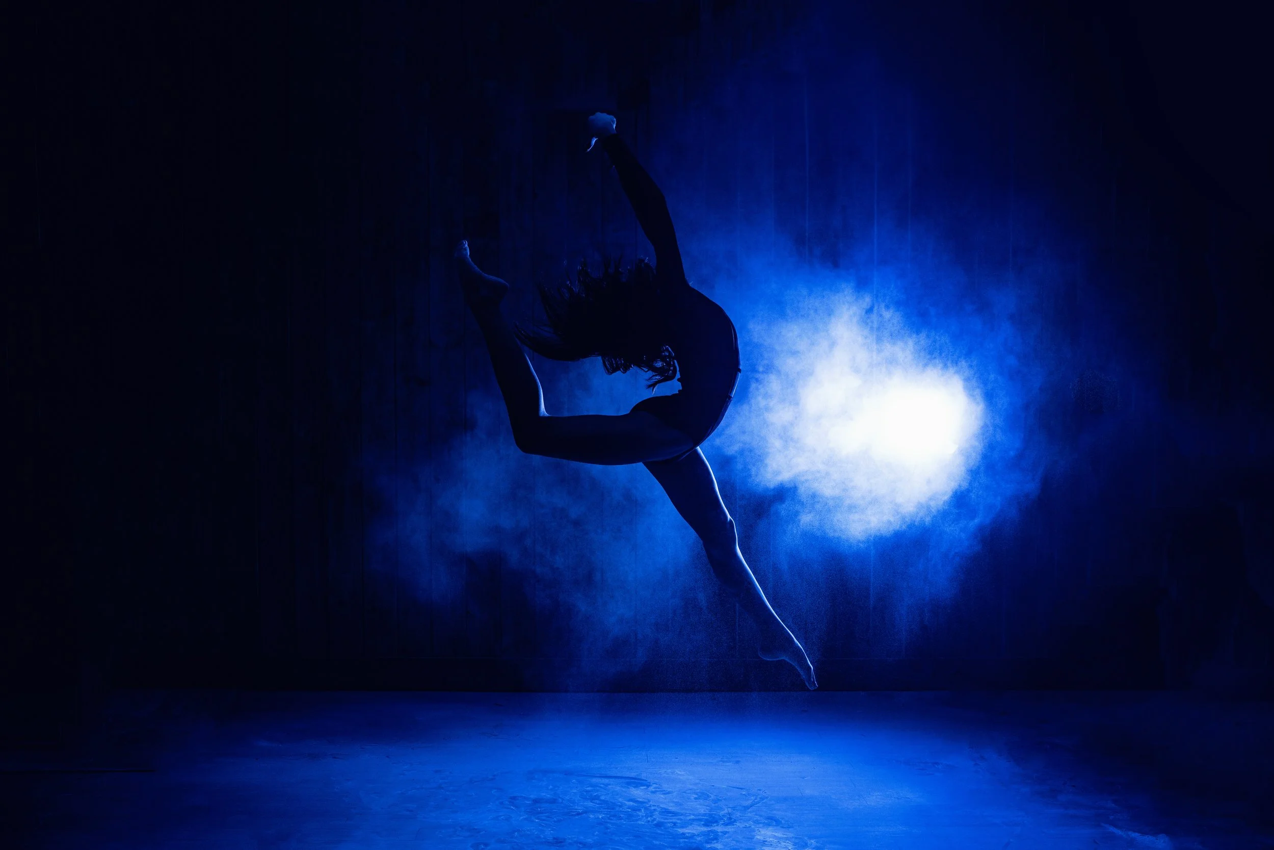 Airborne dancer photographed in dramatic blue light