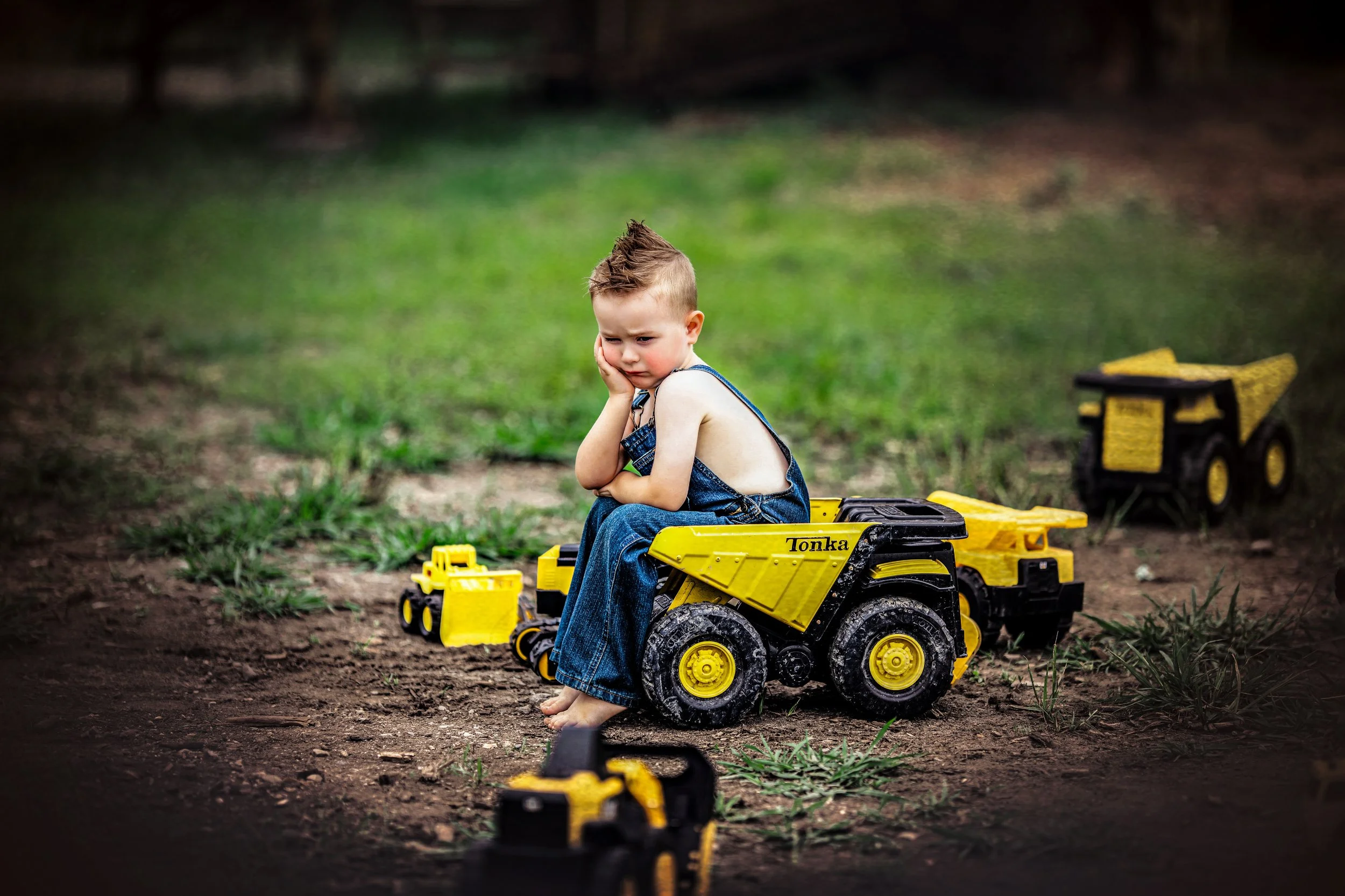 Child sitting on a toy dump truck during the Mud and Trucks portrait experience