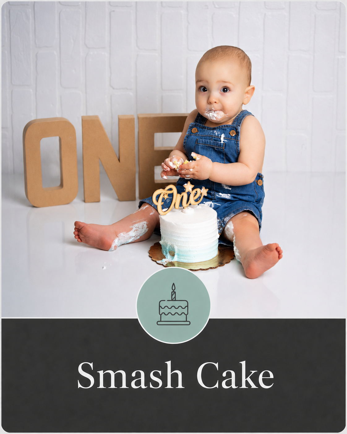 A young child celebrating their first birthday, sitting on the floor with a small white cake in front of them, decorated with a gold "One" topper. The child is wearing denim overalls and has some cake and frosting on their face, hands, and legs. Behind the child, large cardboard letters spell "ONE" and there is a photo that indicates the theme is "Smash Cake."