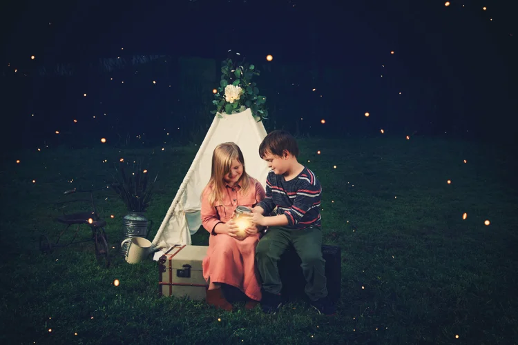Child surrounded by blue-hour color and glowing fireflies
