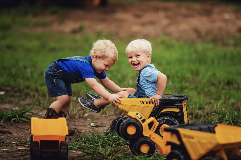 Two children sharing a favorite toy dump truck