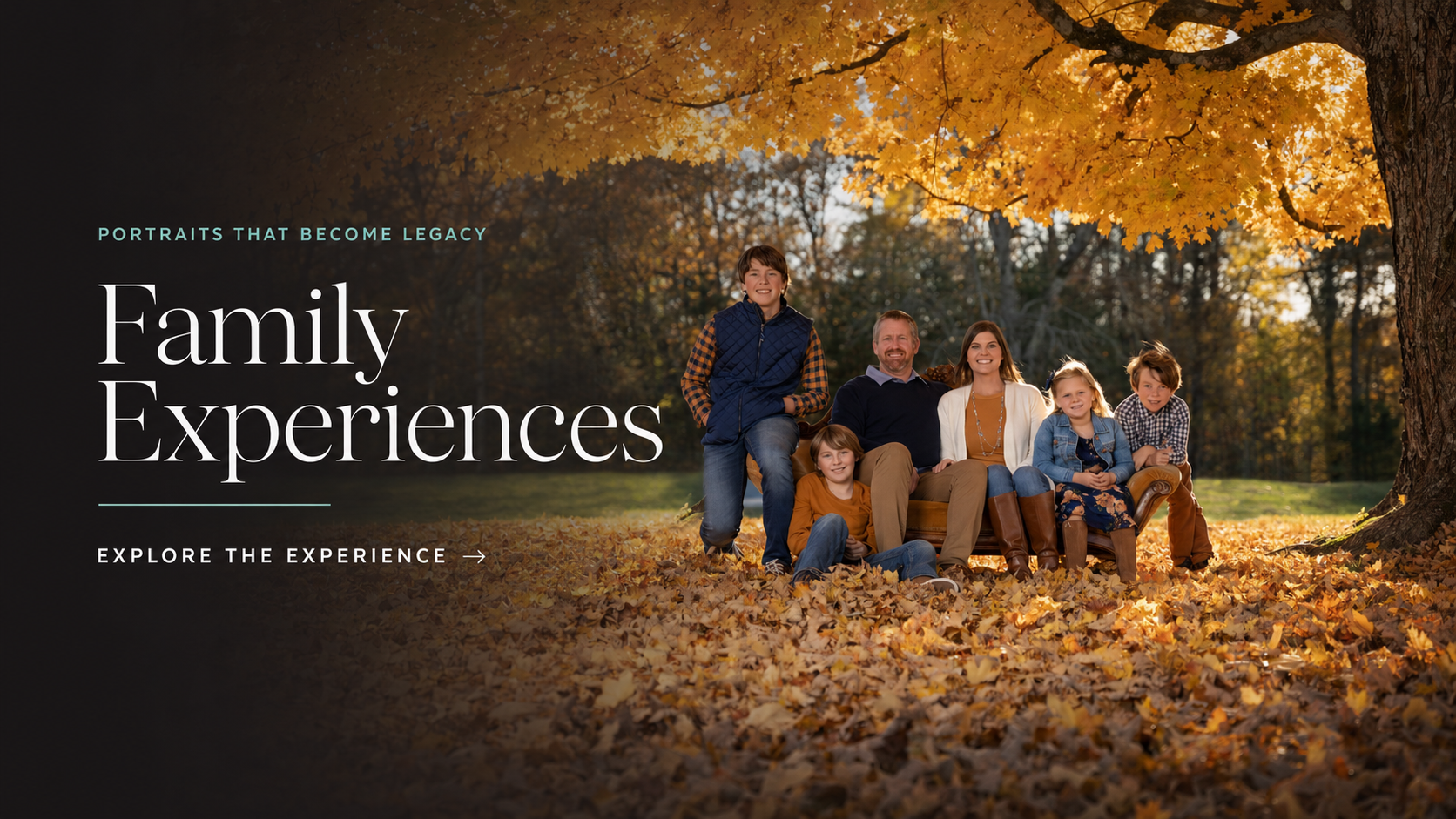 A family of six sitting and standing outdoors on a bed of fallen autumn leaves under a large tree with yellow leaves, smiling. The background features a forest with trees, and the scene is bathed in warm sunlight.