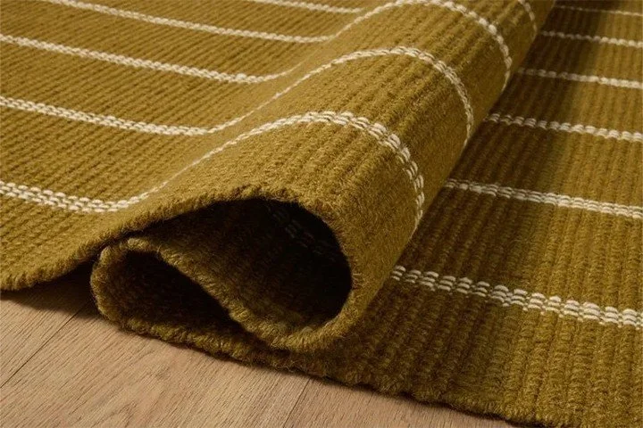 The rug by Amber Lewis x Loloi is a classic striped flatweave area rug in the interior designer's signature warm, earthy tones. The rug has a chunky wool pile with whipstitch borders that add character and natural texture to living rooms, bedrooms, a