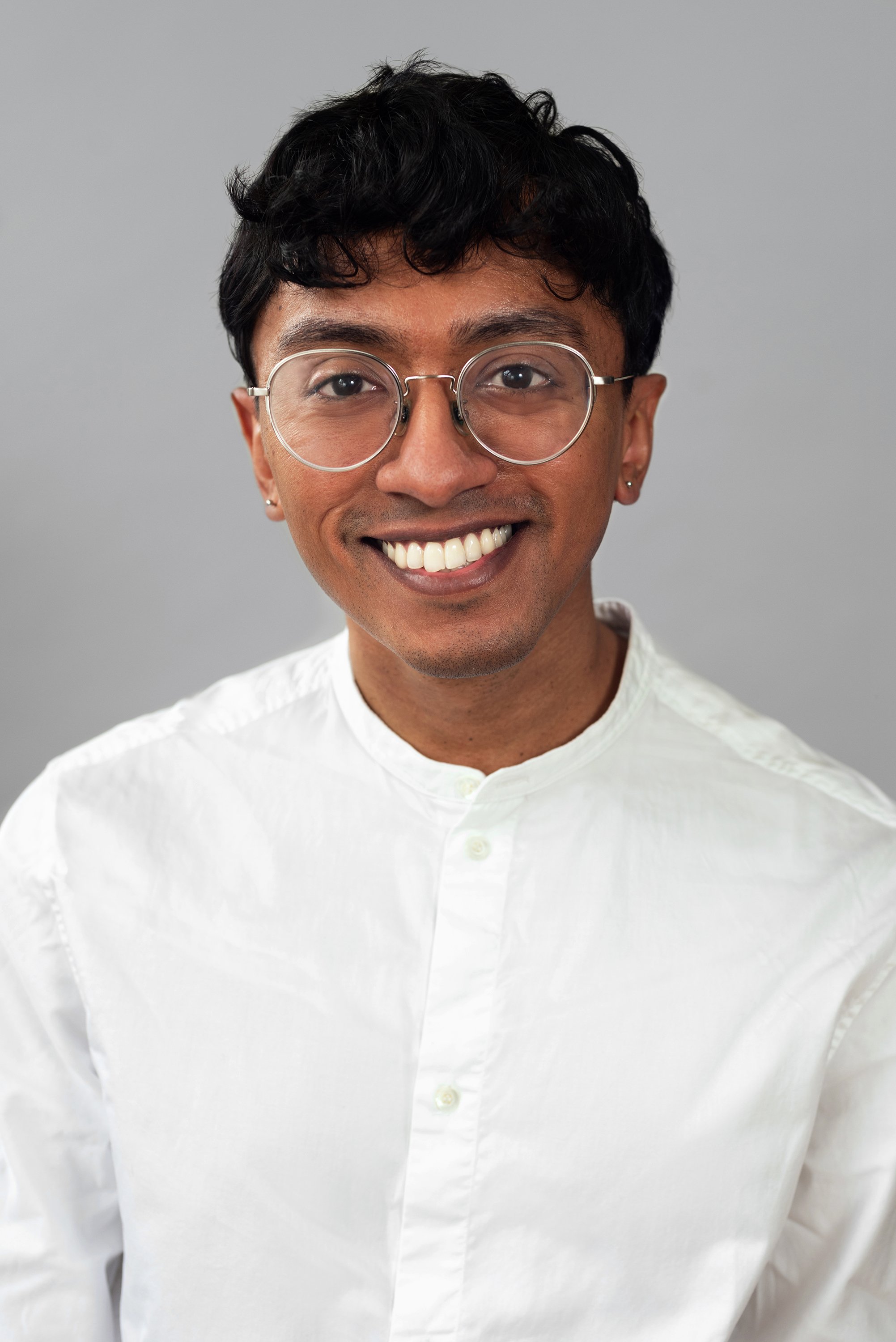  Corporate headshot of man in a white buttoned top and glasses by Ari Scott, NYC headshot photographer. 