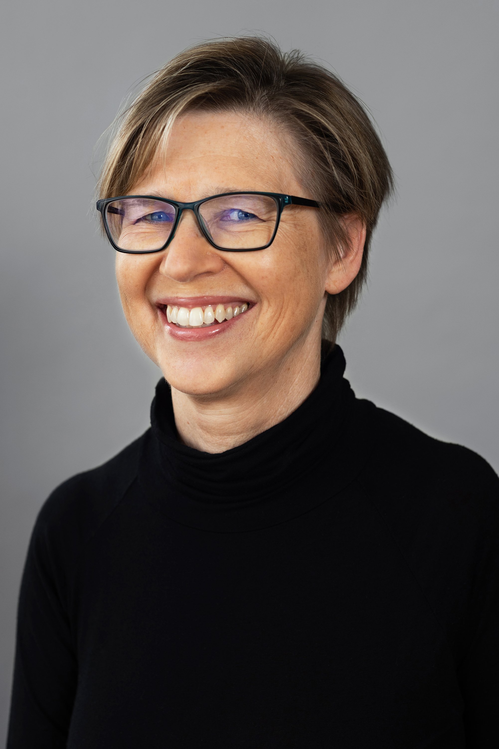  Corporate headshot of woman in a black top and glasses by Ari Scott, NYC headshot photographer. 