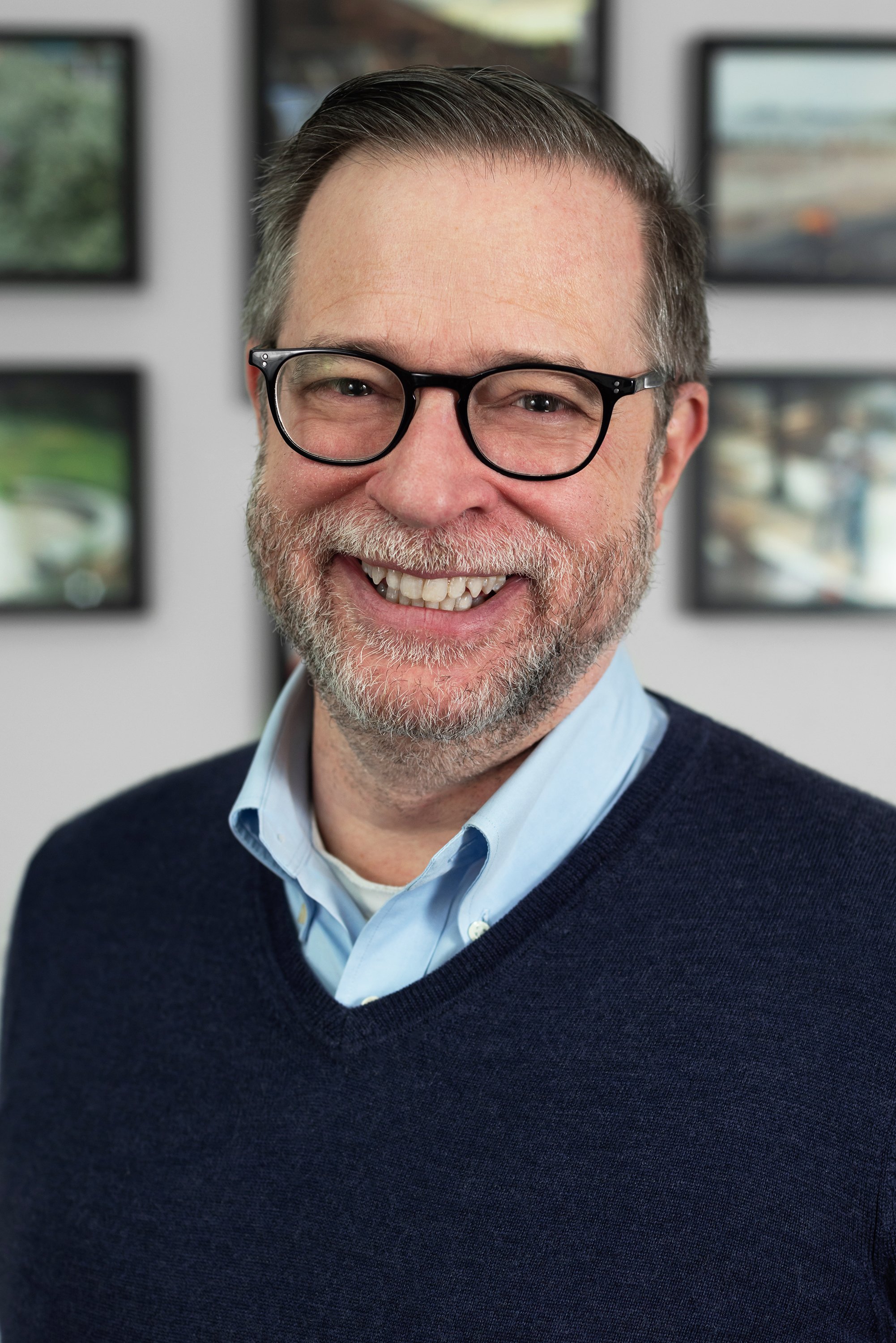 Corporate headshot of man in a blue sweater and glasses by Ari Scott, NYC headshot photographer. 