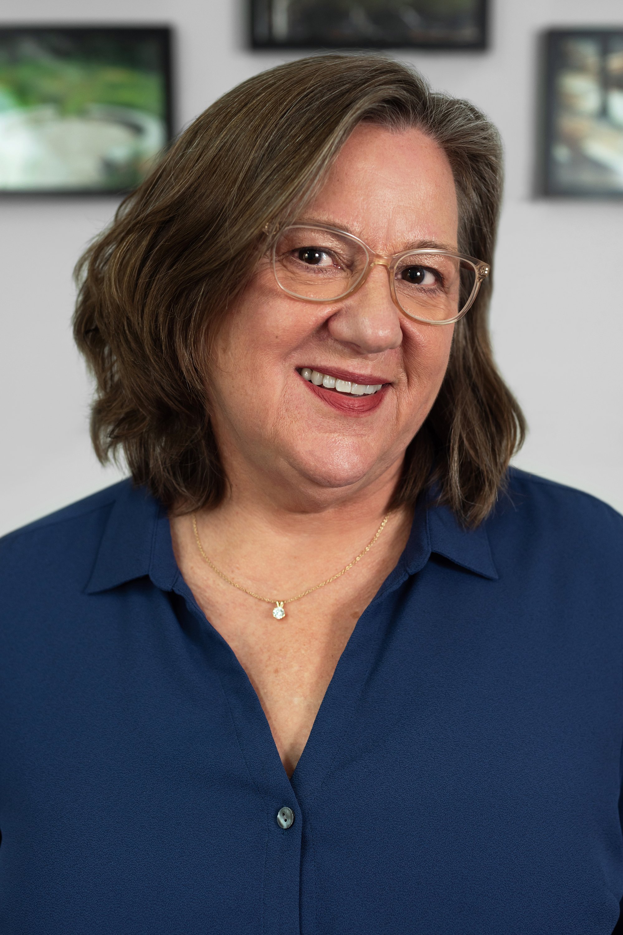  Corporate headshot of woman in blue top and glasses by Ari Scott, NYC headshot photographer. 