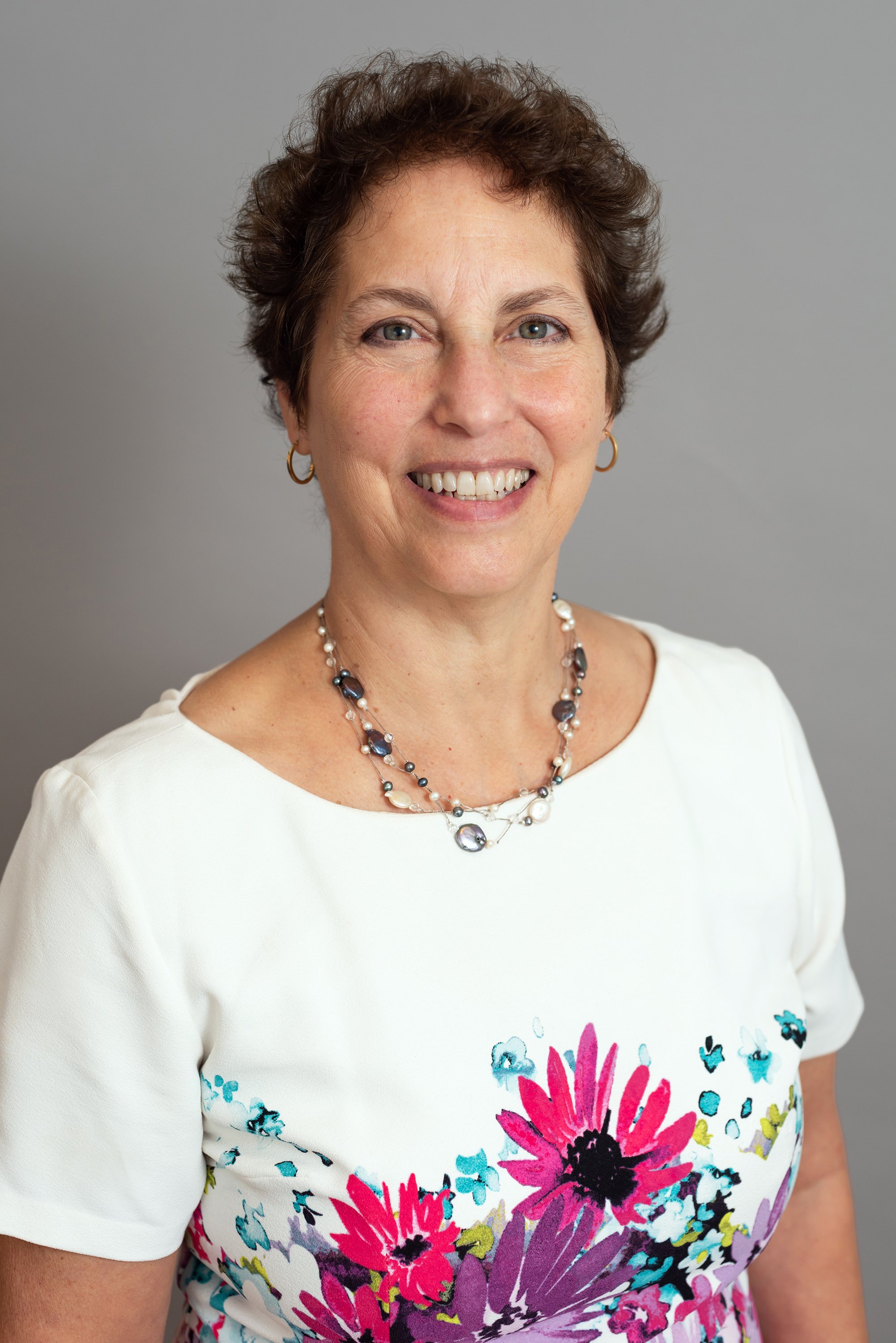  Corporate headshot of a woman in white and flowered dress by Ari Scott, NYC headshot photographer. 