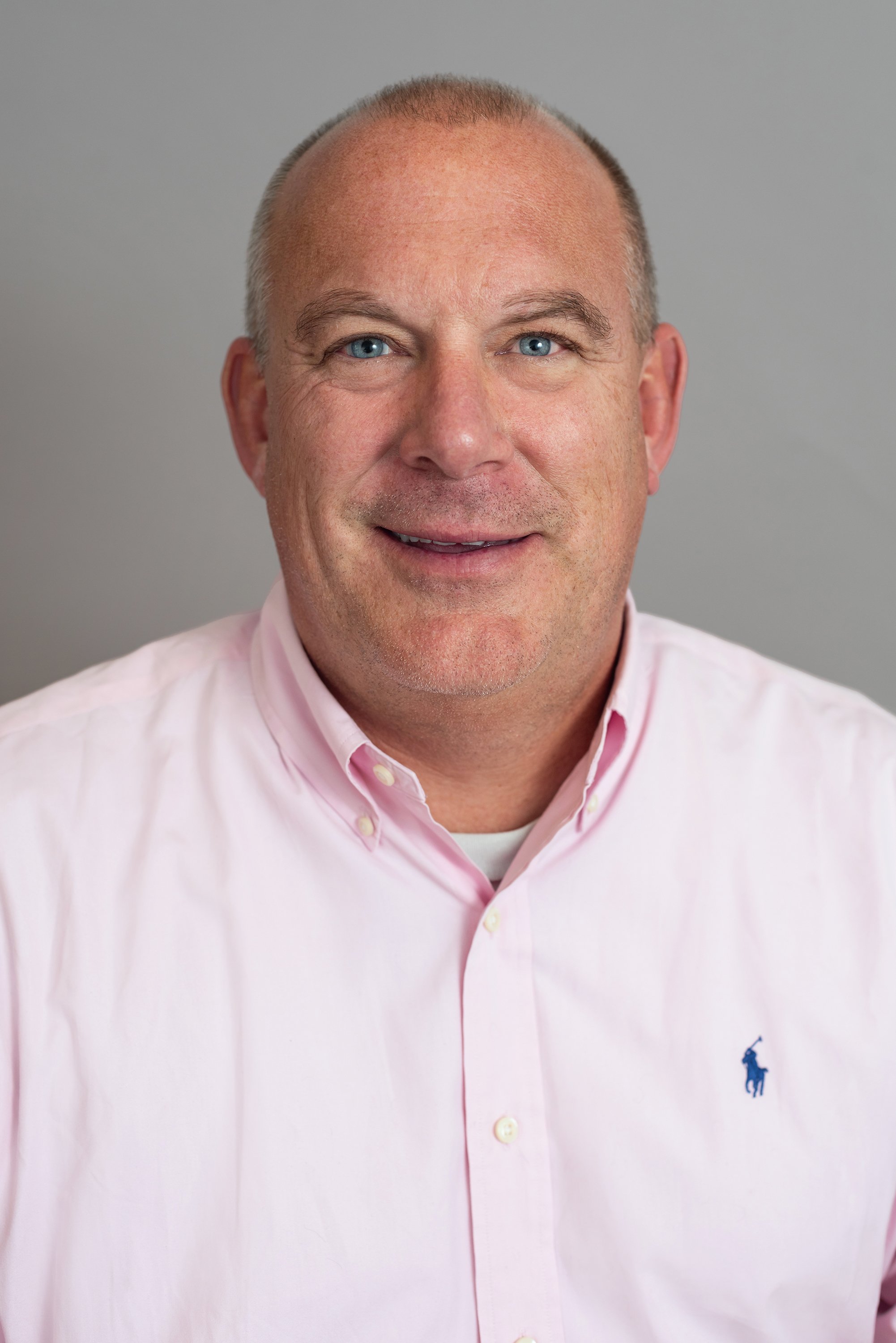  Corporate headshot of a man wearing a pink button down shirt by Ari Scott, NYC headshot photographer. 