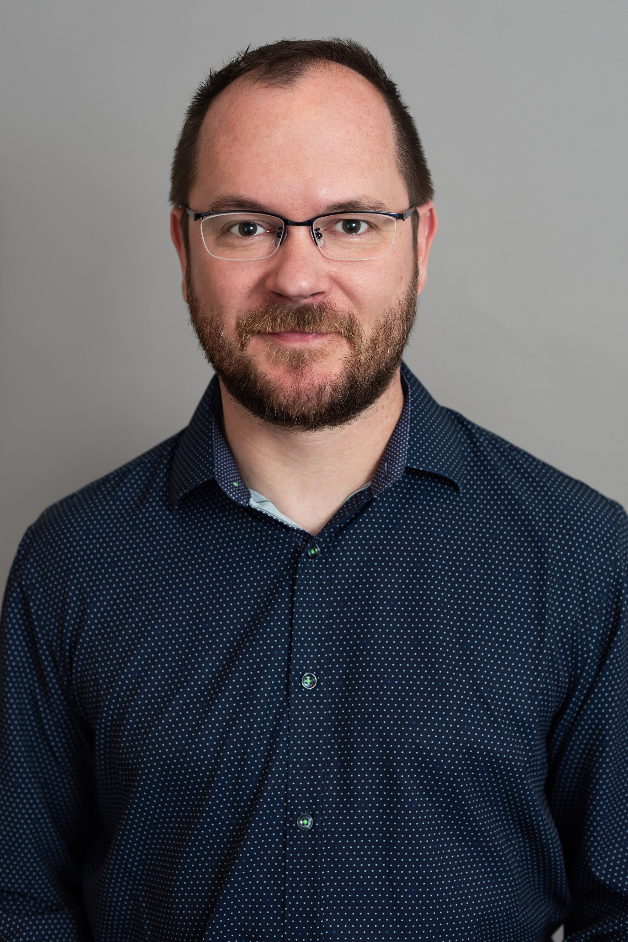  Corporate headshot of a man in a dark blue shirt shirt by Ari Scott, NYC headshot photographer. 