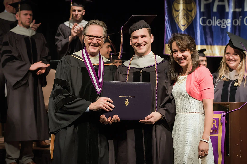 Dr. Meeker, President of Palmer College- West, and Dr. Erica Heppe presenting Dr. SCott heppe his doctor of chiropractic diploma. 